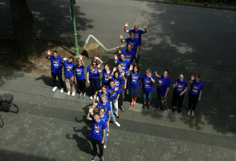 Menschen in blauer Kleidung bilden gemeinsam ein Plus